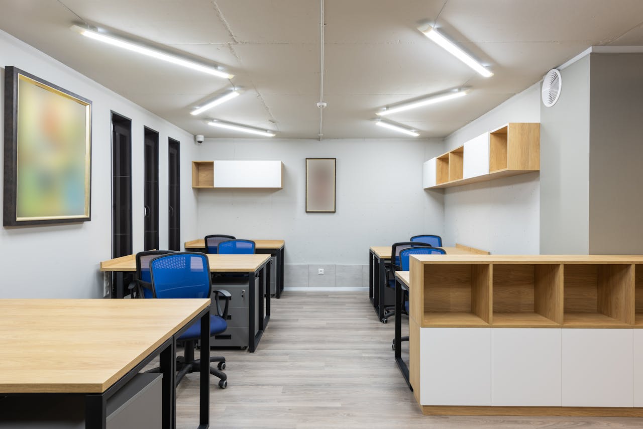 Interior of contemporary workspace with office chairs at tables and wooden shelves under ceiling with geometric lamps
